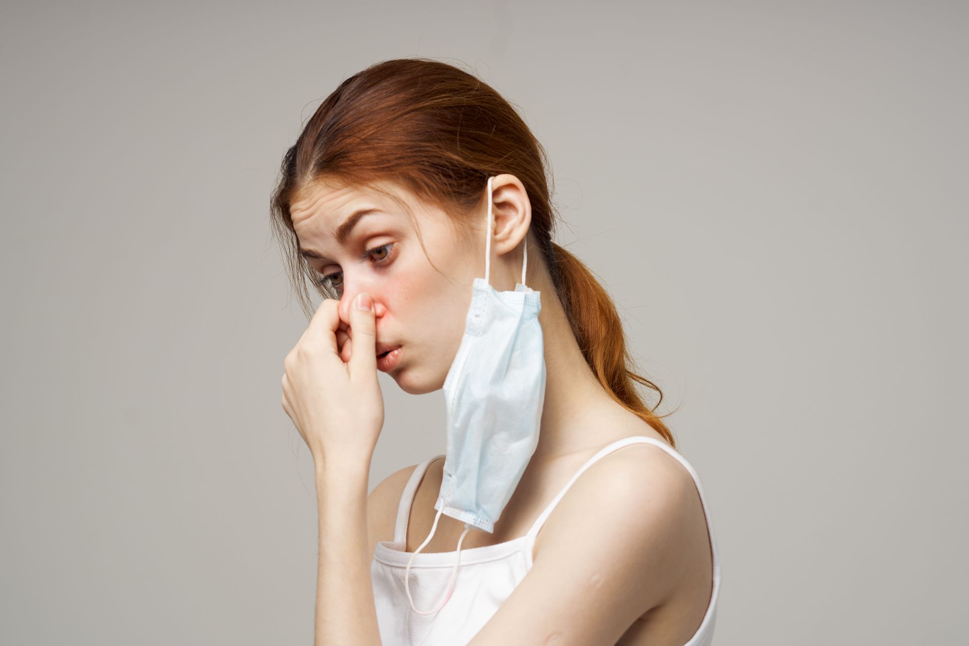 A woman with recurring rhinosinusitis wearing a medical mask is covering her nose.