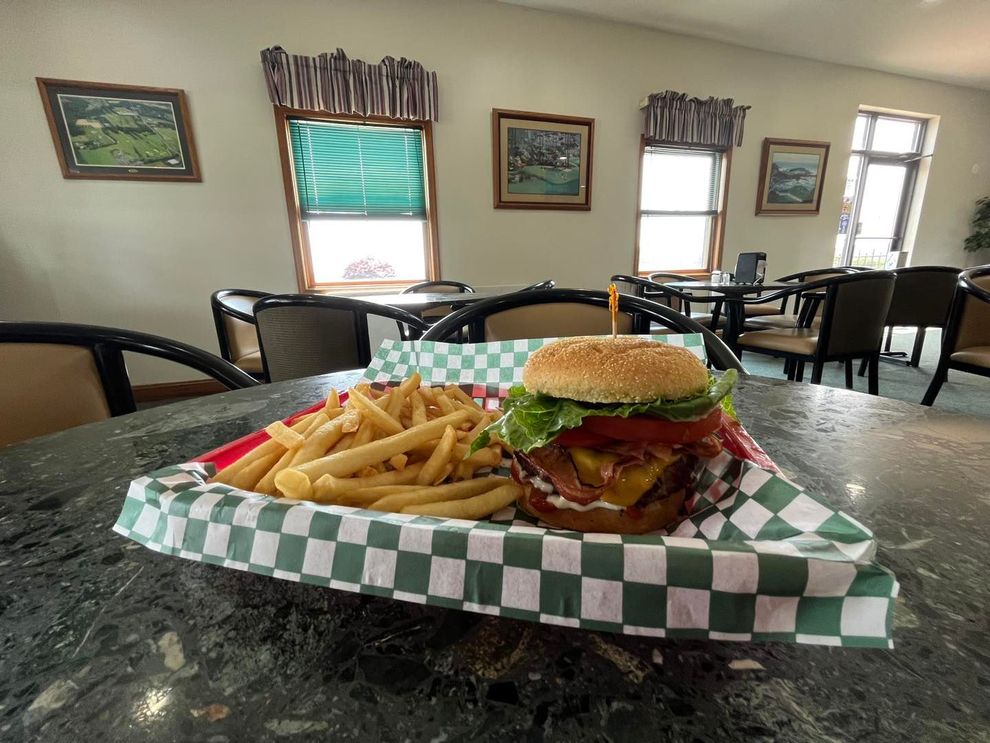 A hamburger and french fries are on a checkered paper on a table.