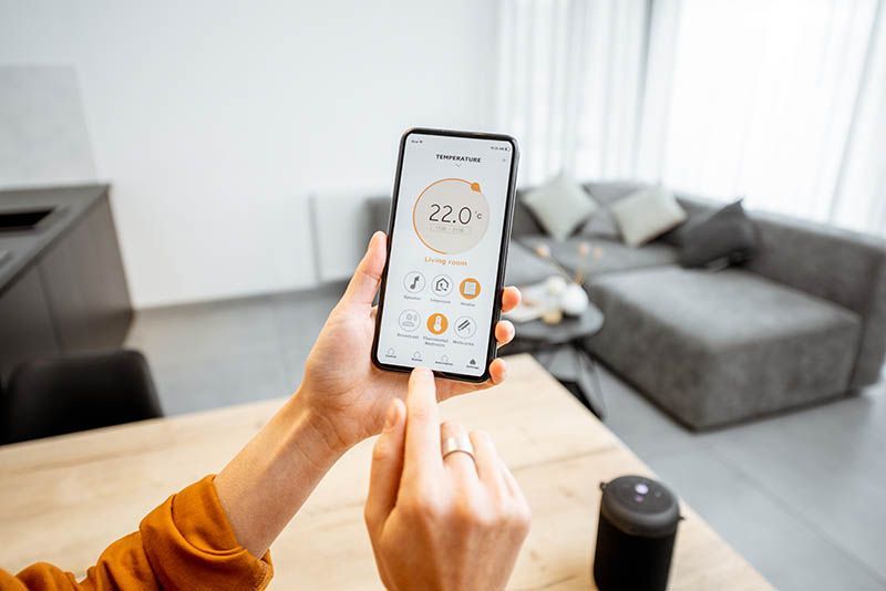 A person is using a smart phone to control the temperature in their living room.