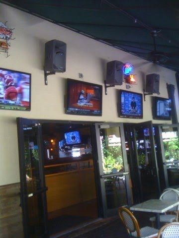A row of televisions hanging on a wall in a restaurant