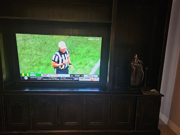 A large flat screen tv is sitting on top of a wooden entertainment center.