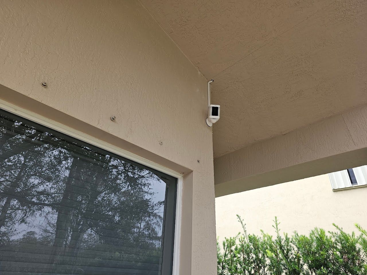 A security camera is mounted on the side of a building next to a window.