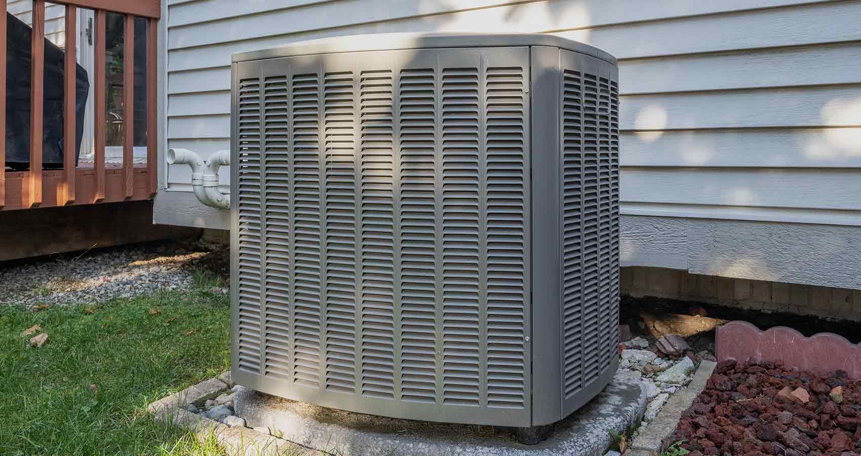 An air conditioner is sitting on the side of a house.