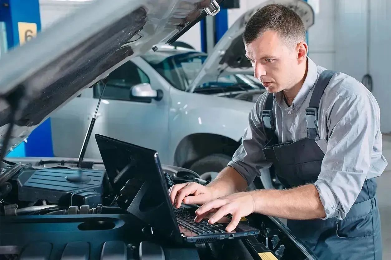 Mechanic performing a vehicle engine performance test using a laptop