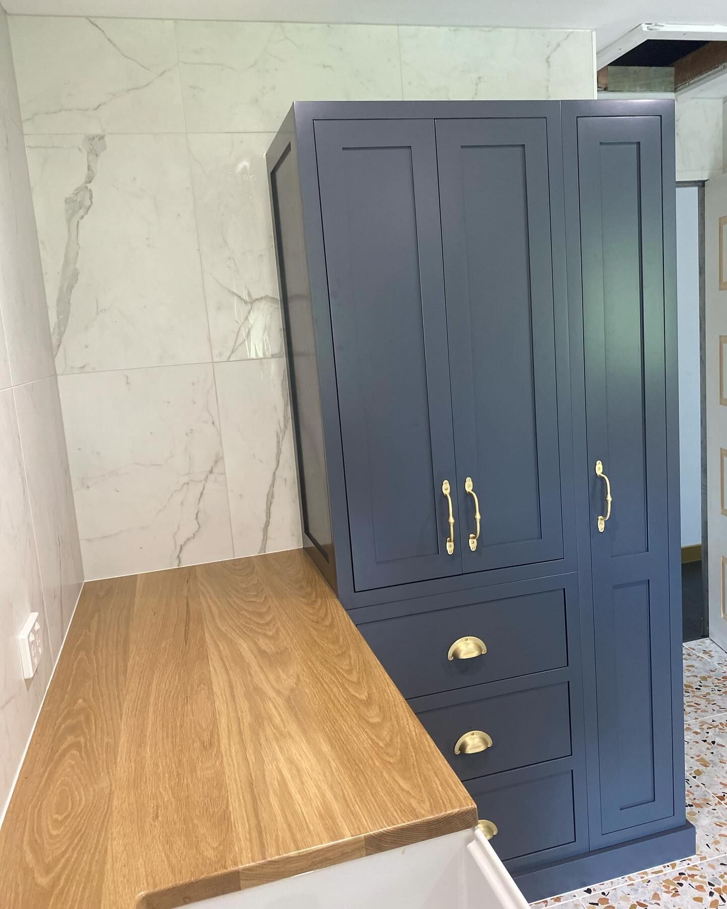 Wooden countertop with gray cabinet, gold hardware, marble tile backdrop. — BC Customs in Burrell Creek, NSW
