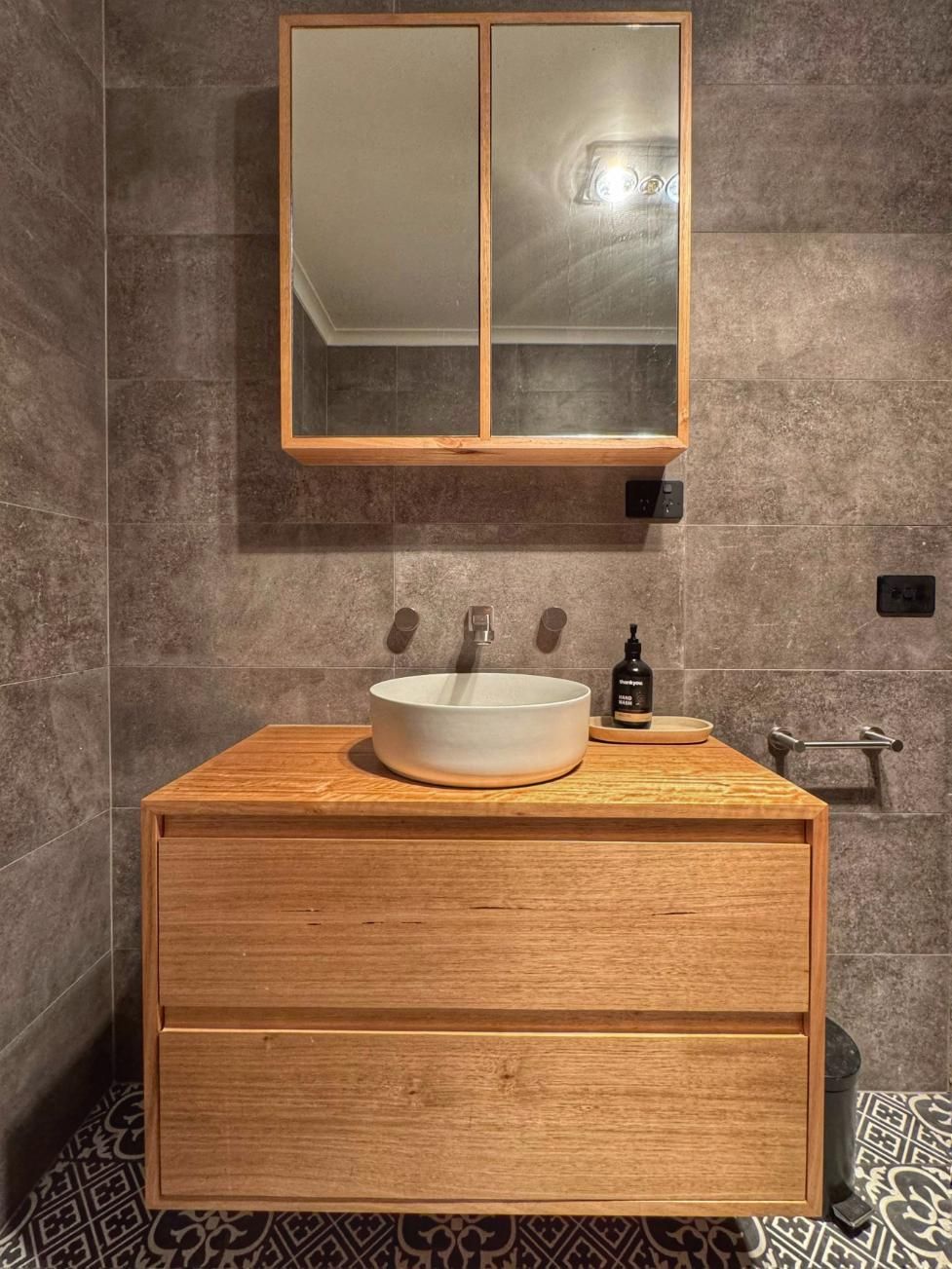 Bathroom With Wooden Vanity, Round Sink, Mirrored Cabinet, Gray Tile Wall — BC Customs in Port Macquarie, NSW