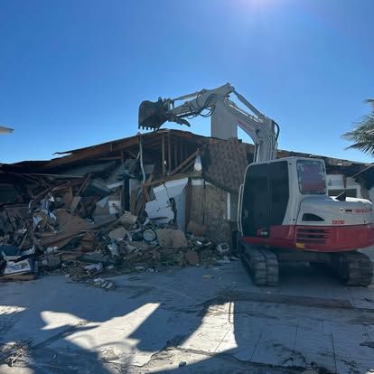 A red and white excavator is demolishing a house.