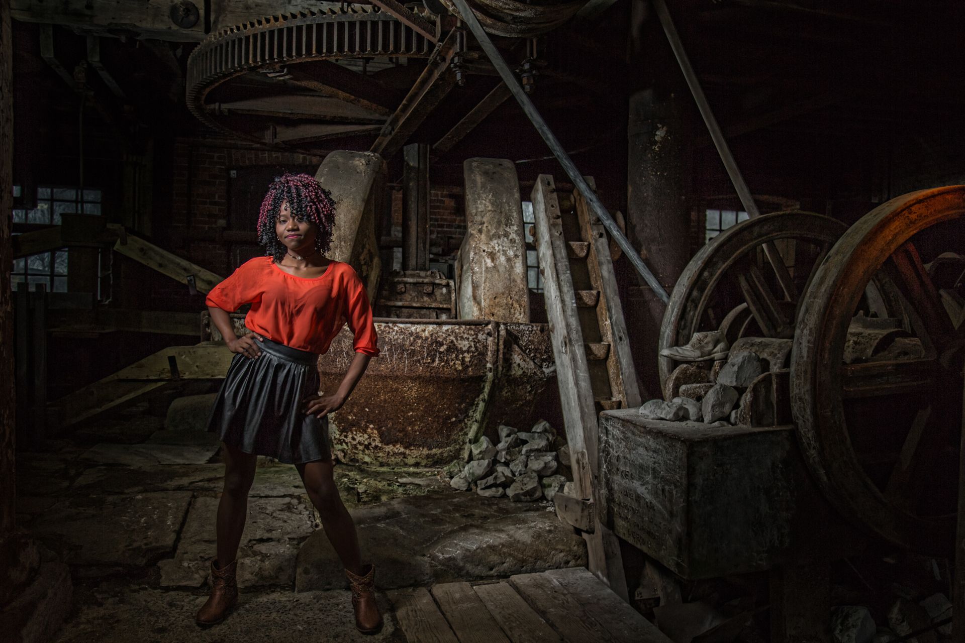 A woman is standing in a dark room with a wagon wheel in the background.