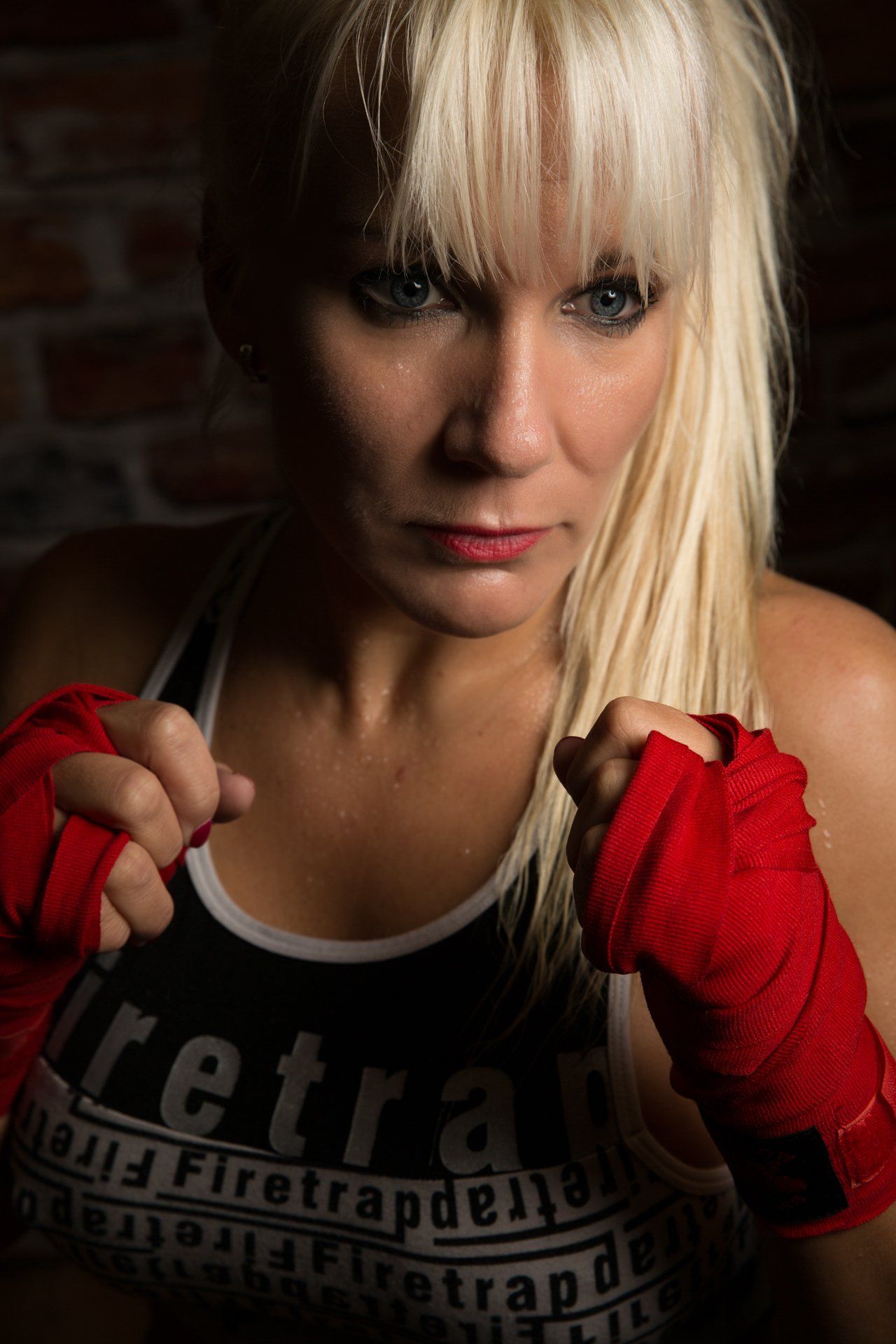 A woman is wearing red boxing gloves and a black tank top.