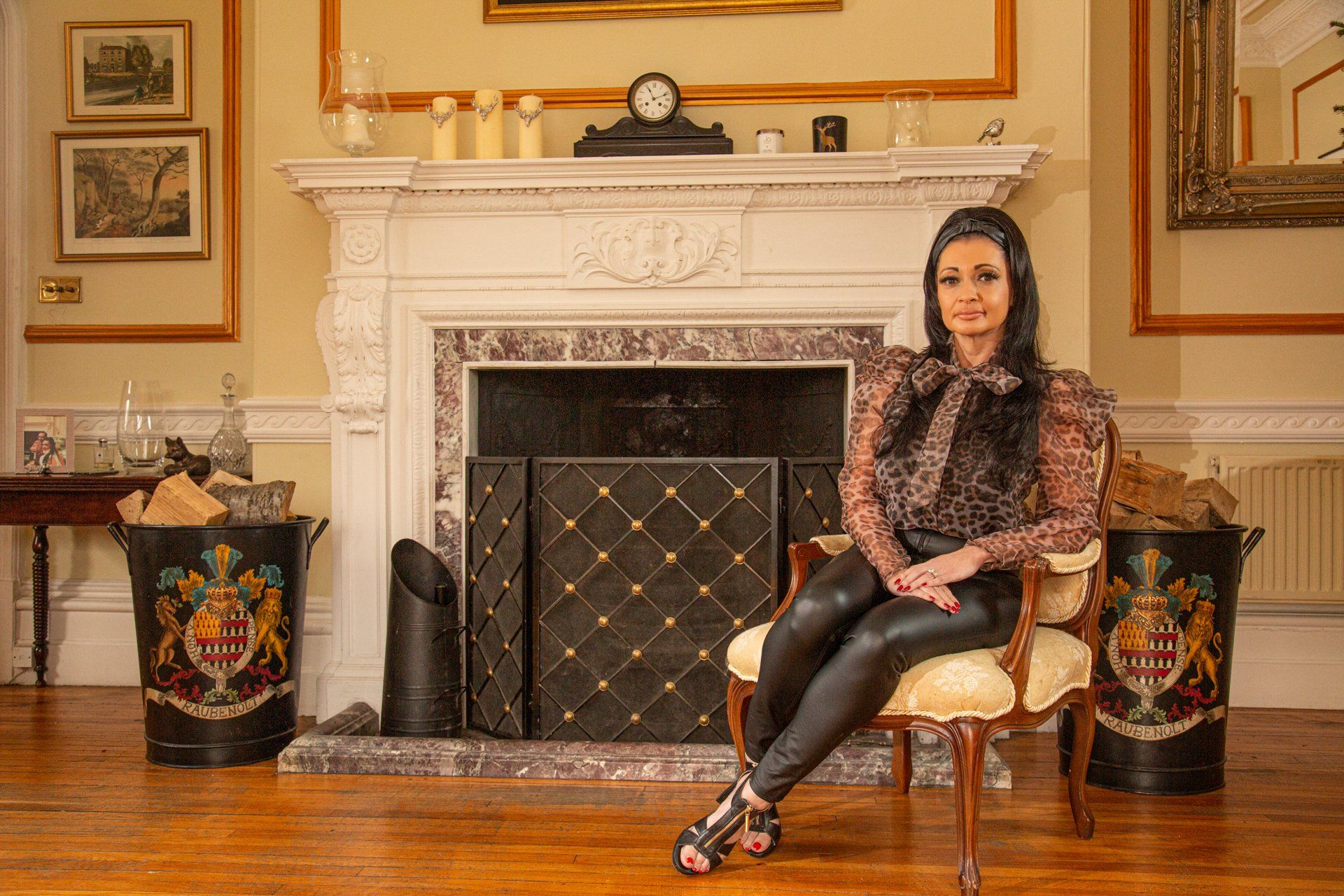 Portrait of woman in leopard print seated in front of large fireplace