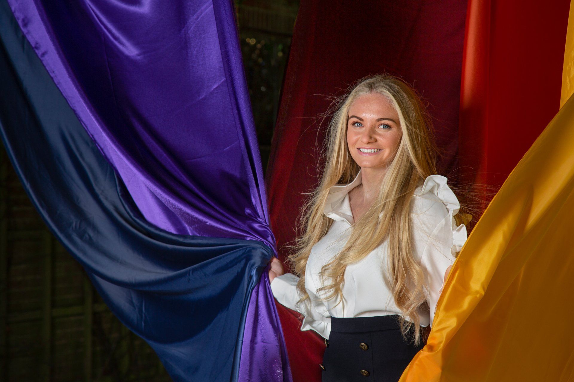 Young female business owner amongst vibrant silks draped across the Arcade in Valley Park, Harrogate