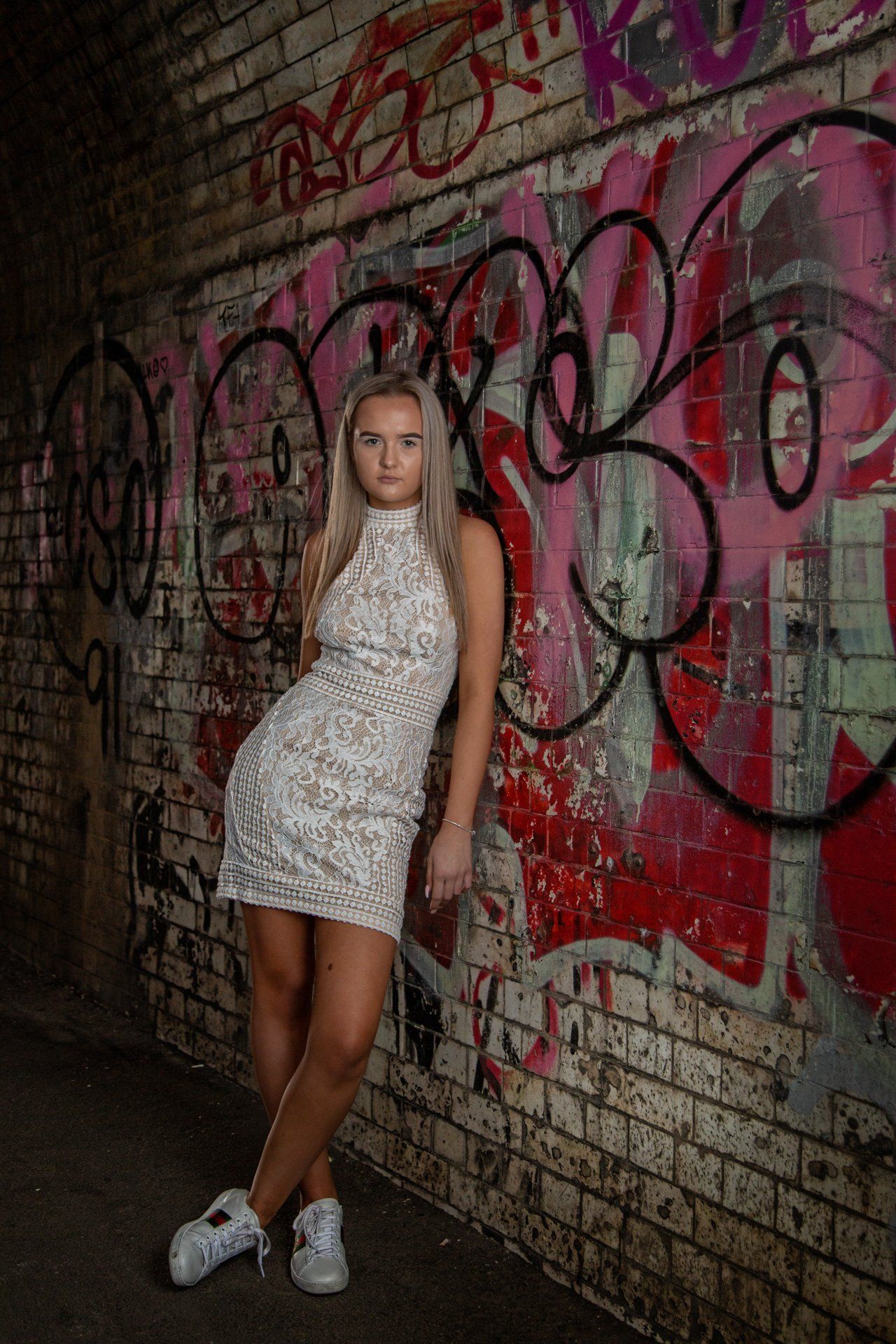 Teenager photography captures girl wearing a white lace dress and trainers in graffiti tunnel, Leeds
