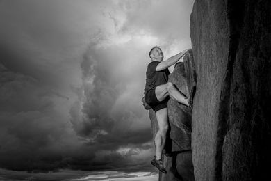 A black and white photo of a man climbing a rock wall.