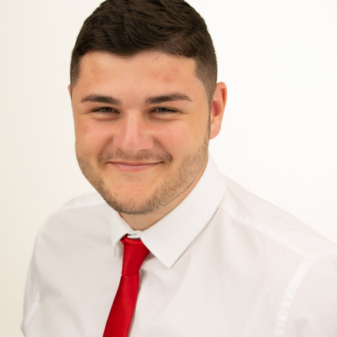 Headshot taken in Leeds photography studio of dark haired man wearing red tie