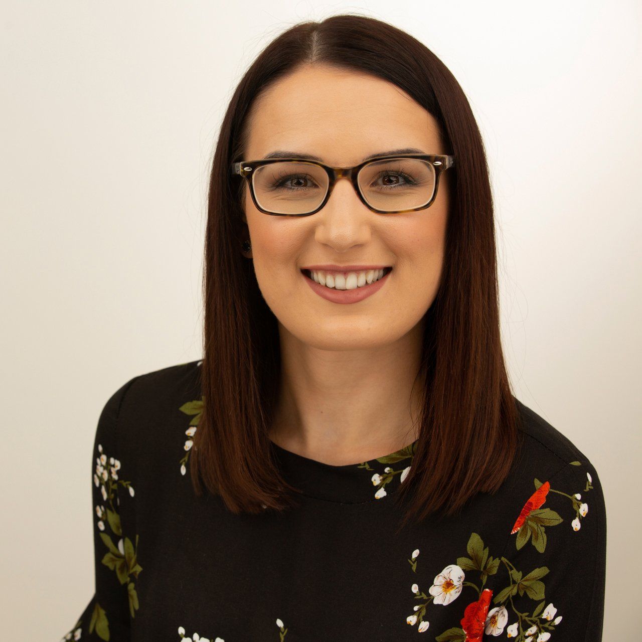 Headshot taken in Leeds photography studio of dark haired woman wearing red and black top