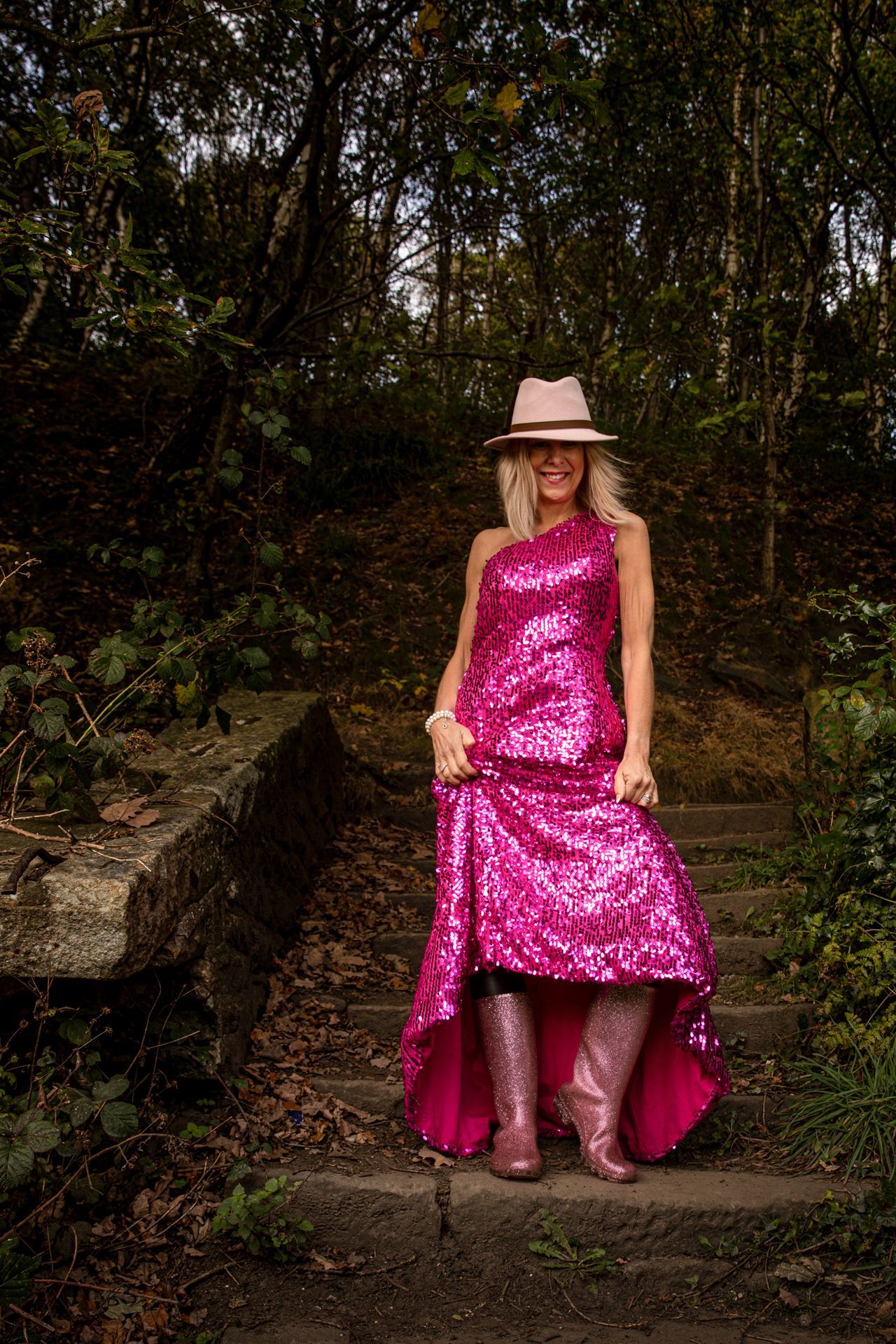 Mandy Taylor MBE wearing pink evening dress, hat and sparkly wellies on steps at Golcar.