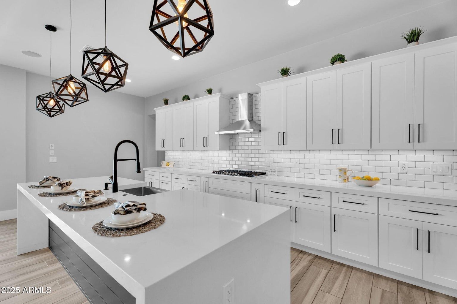 Bright white modern kitchen with large island, pendant lights, and place settings on the counter