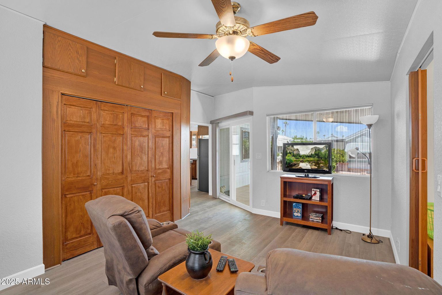 Bright living room with wood-paneled closet, ceiling fan, chair, and window view of aquarium