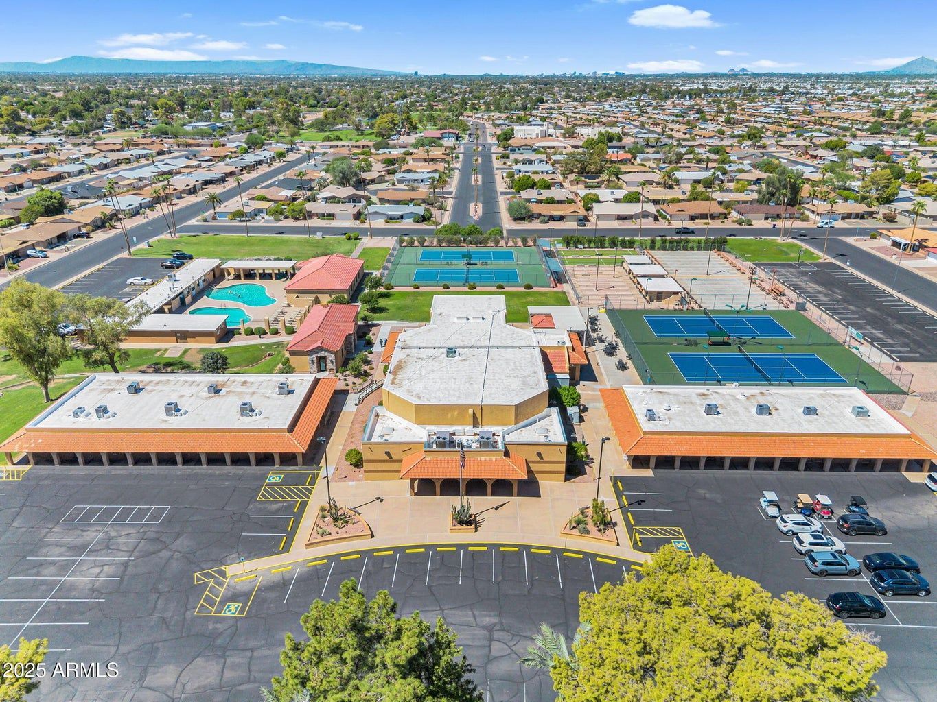 Aerial view of a school campus with sports courts, playgrounds, and parking lots in a suburban neighborhood
