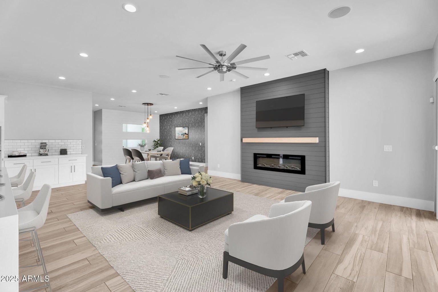 Modern open-concept living room with gray sofa, fireplace TV wall, and light wood flooring