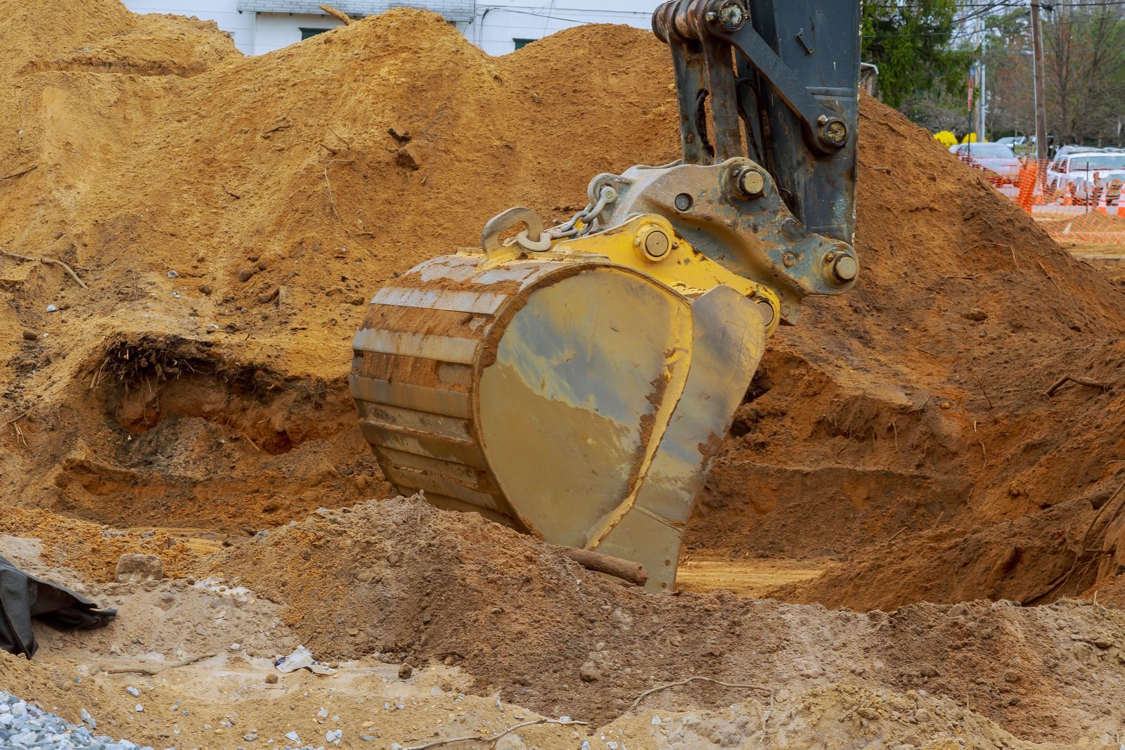 Excavator bucket digging into a pile of dirt at a construction site.