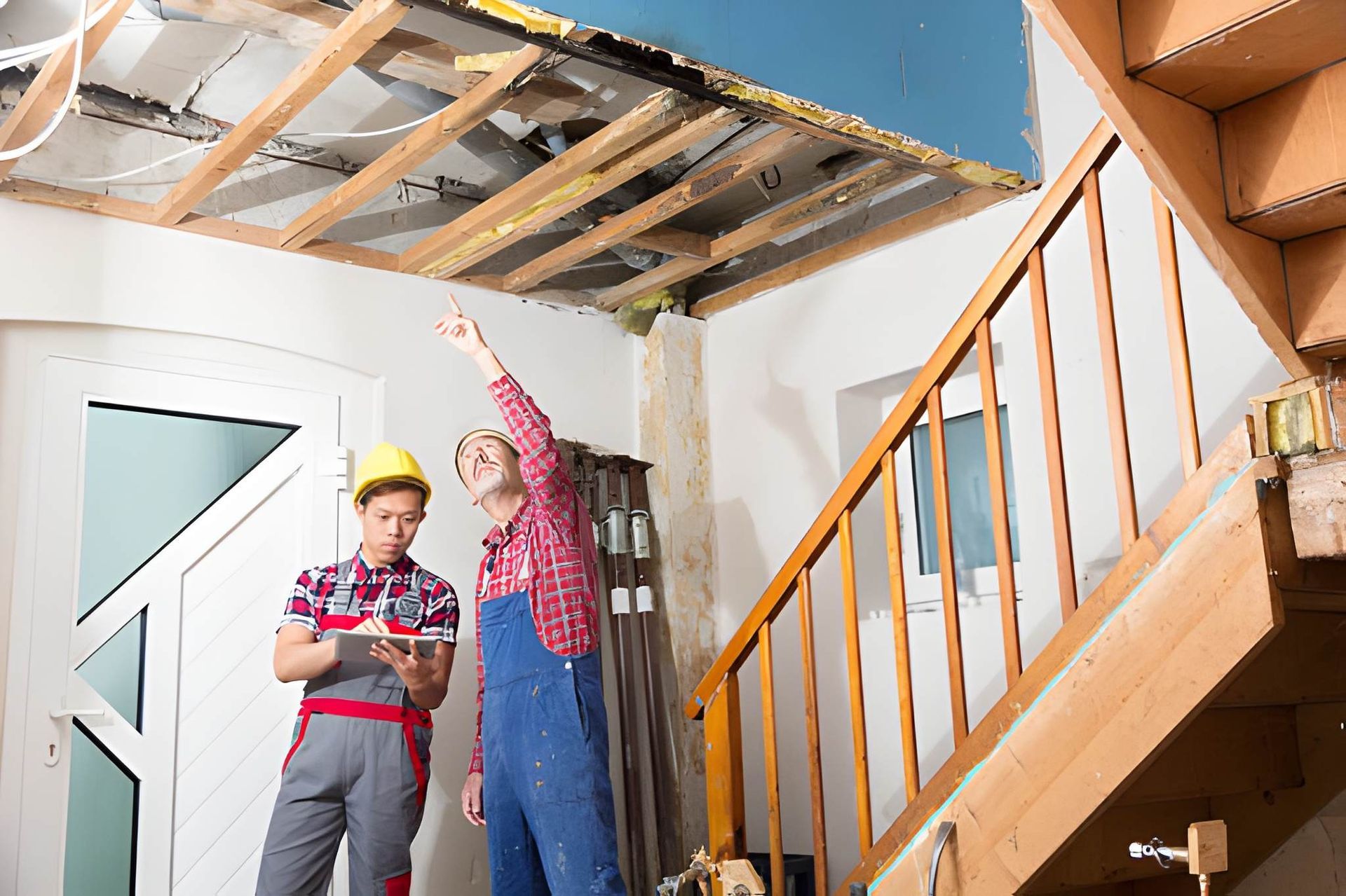 Home inspection Jupiter FL team assessing ceiling structure and interior damage during renovation walkthrough.