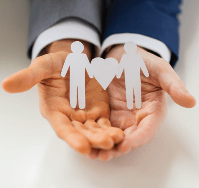 A person is holding two paper people with hearts in their hands