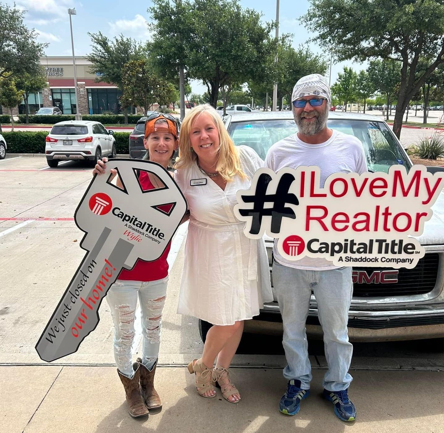 A group of people standing in front of a car holding signs that say i love my realtor