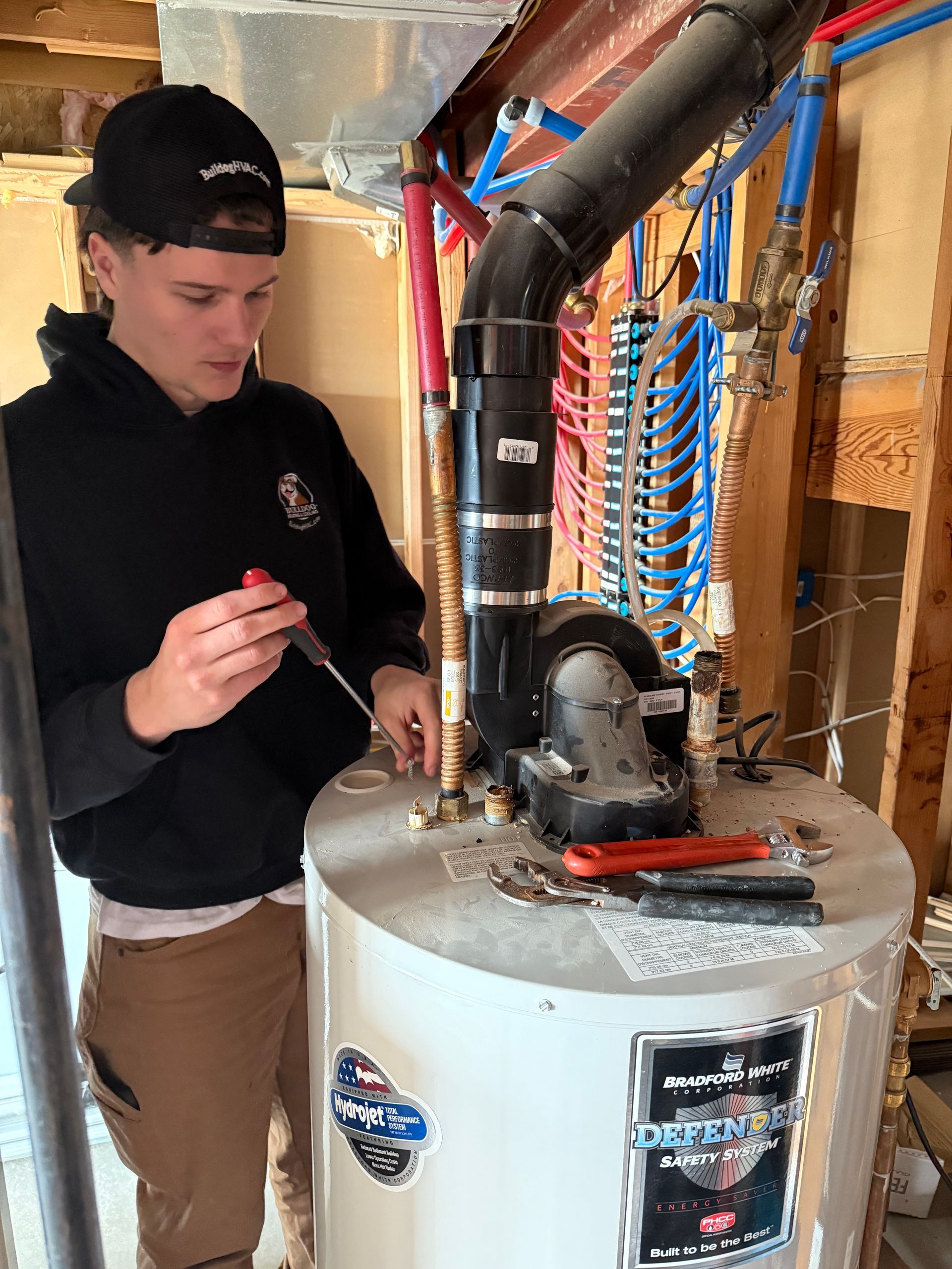 Person adjusting the temperature dial on a white water heater, close-up.