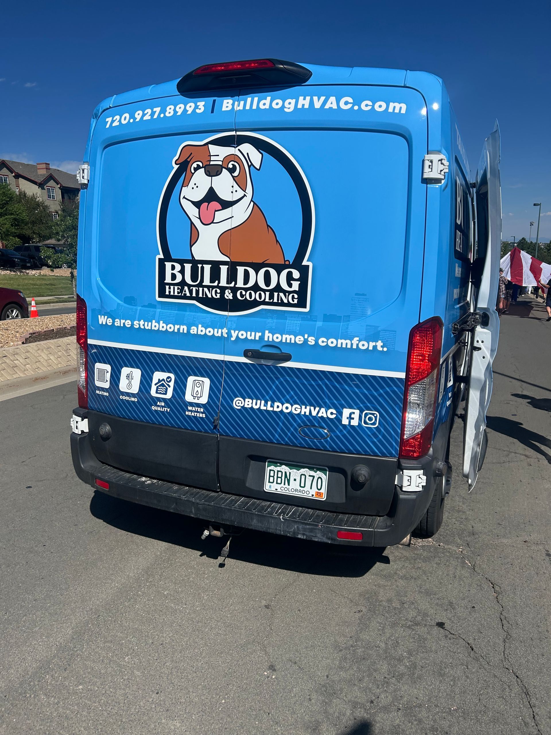 A blue Bulldog Heating & Cooling service van parked on a street with a logo featuring a bulldog illustration.