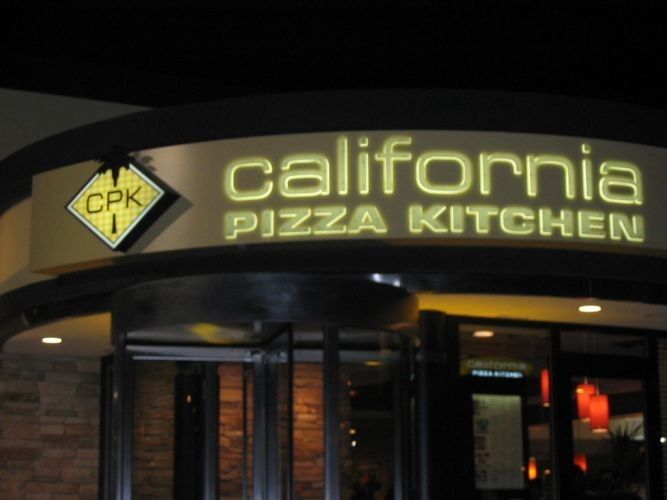 California Pizza Kitchen restaurant entrance at night, lit signage.
