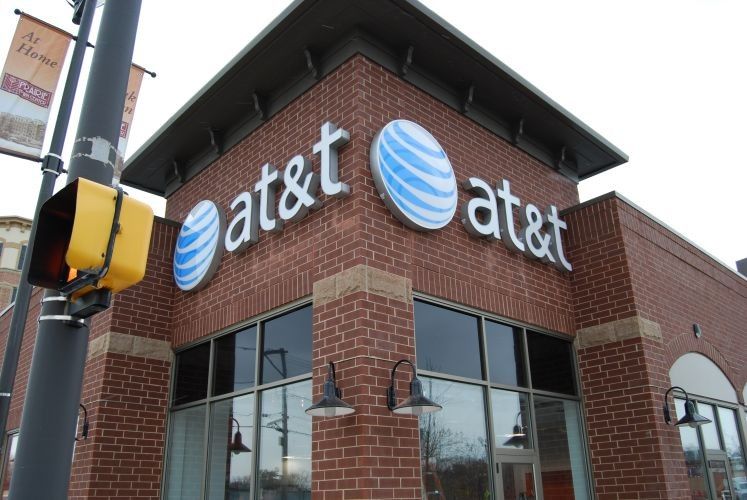 Exterior of an AT&T store with the company logo prominently displayed on a brick building, near a traffic light.