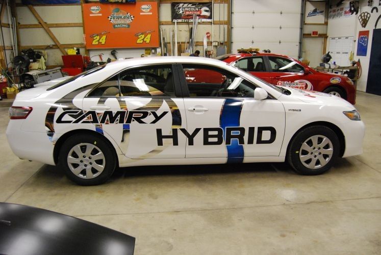 White Toyota Camry Hybrid car with partial blue stripes and
