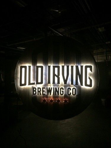 Glowing Old Irving Brewing Co. sign in a dimly lit setting.