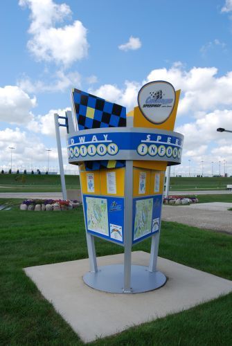 Signpost for the World Wide Technology Raceway, featuring checkered flag and track information, under a blue sky.