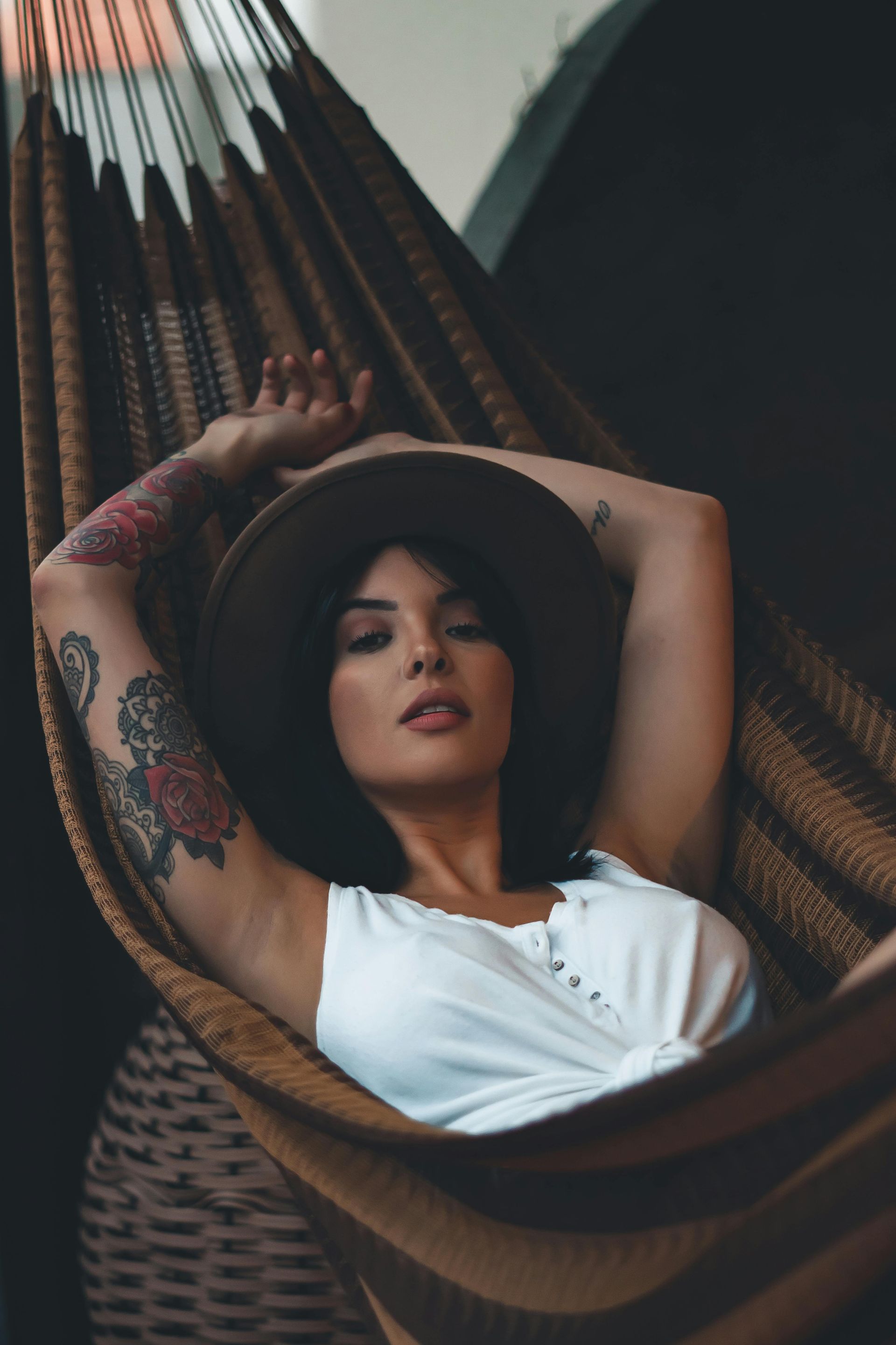 A woman wearing a hat is laying in a hammock.