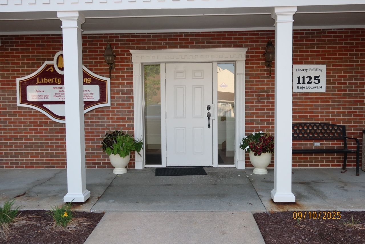 Woman in light blue shirt speaks with person in gray shirt at a reception desk.