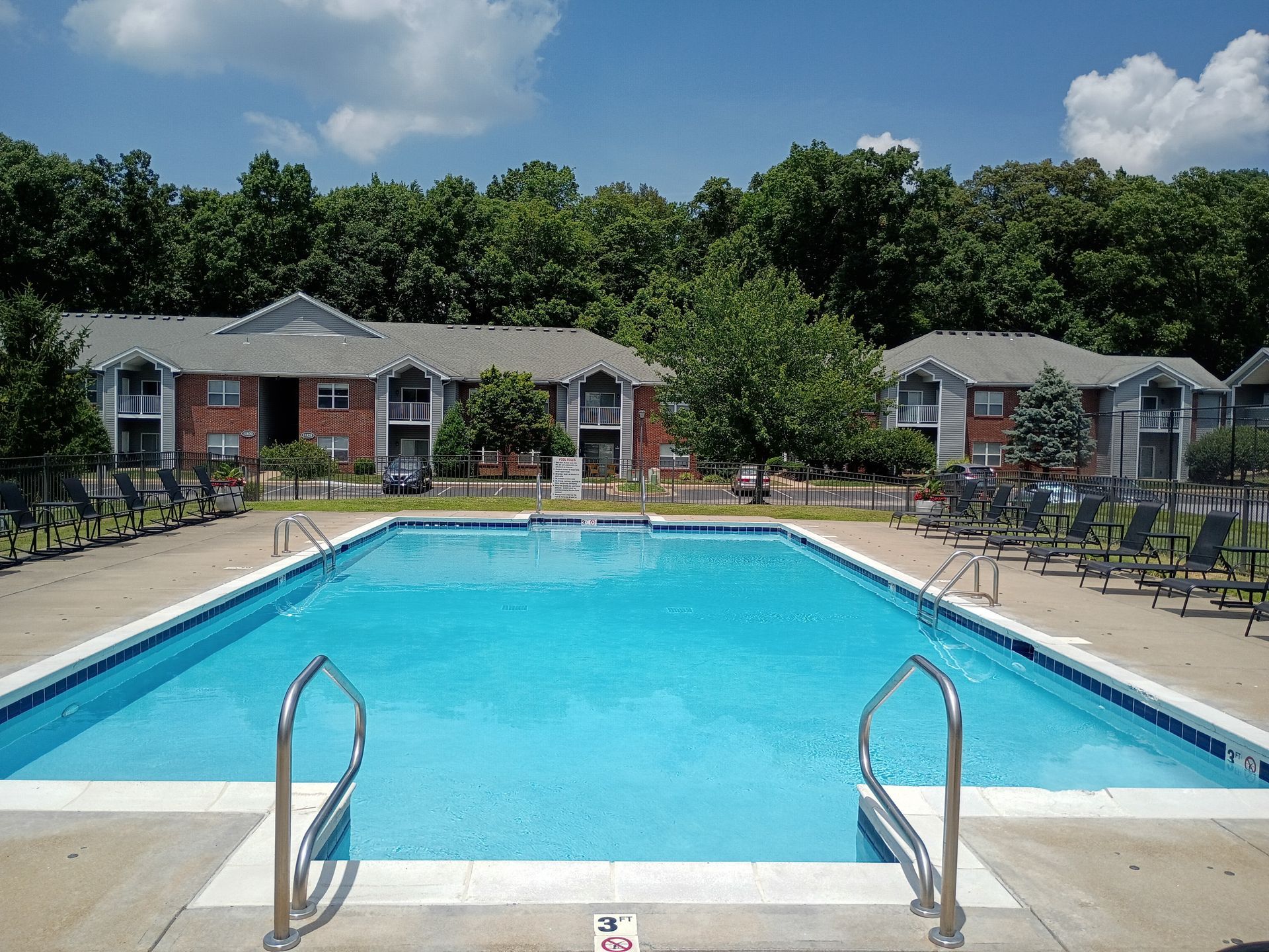 A large swimming pool with chairs and tables around it