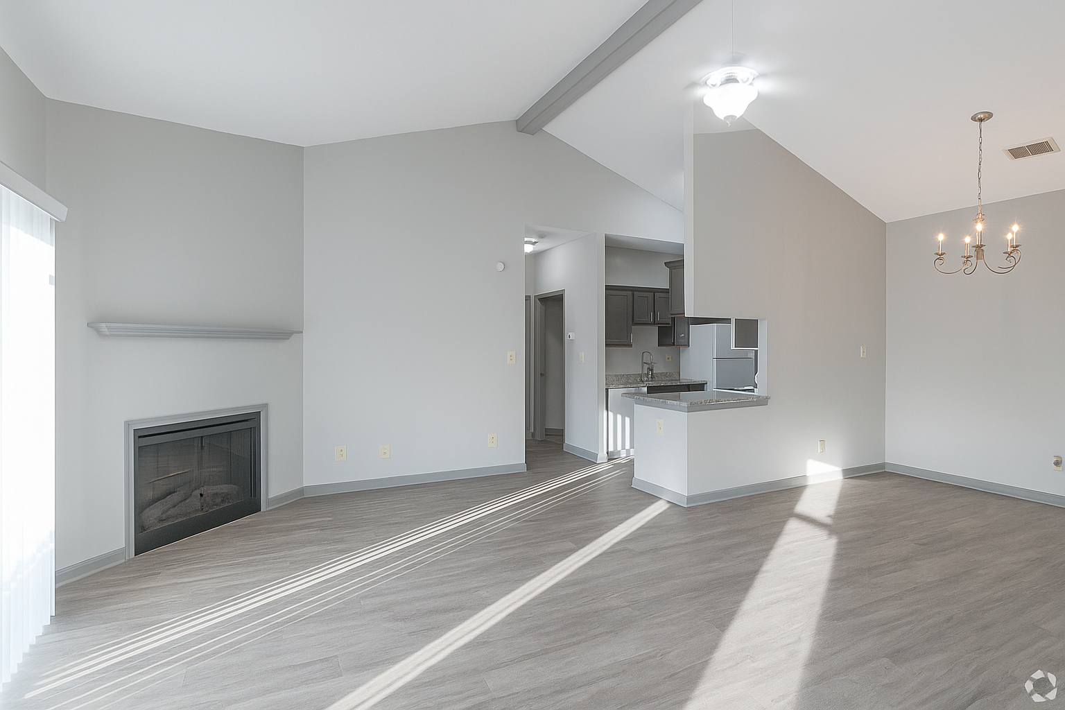 An empty living room with a fireplace and a ceiling fan
