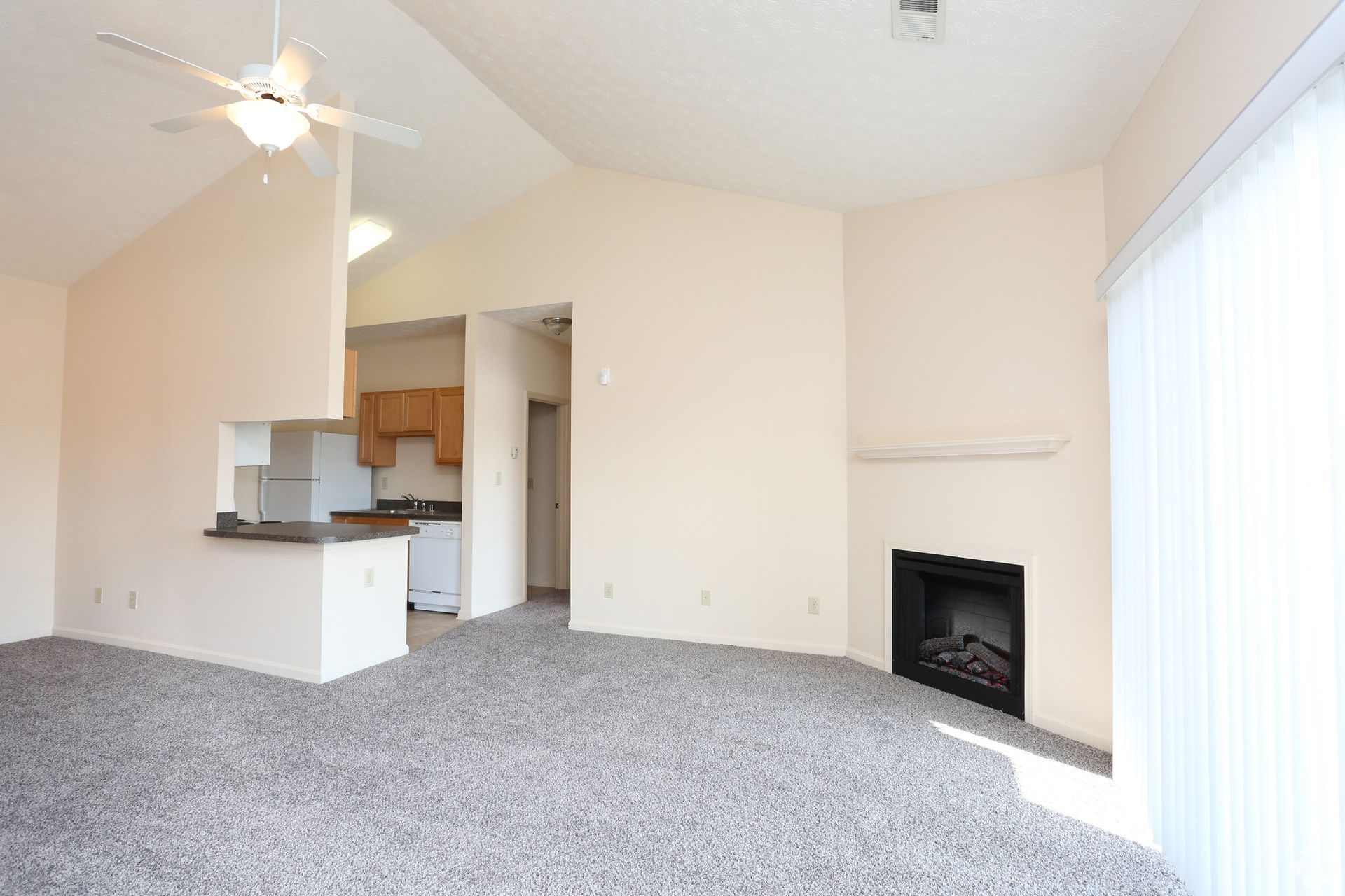 An empty living room with a fireplace and a ceiling fan