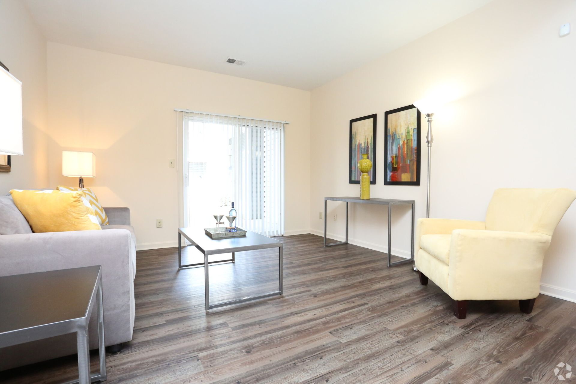 A living room with a couch , chair , coffee table and sliding glass doors.
