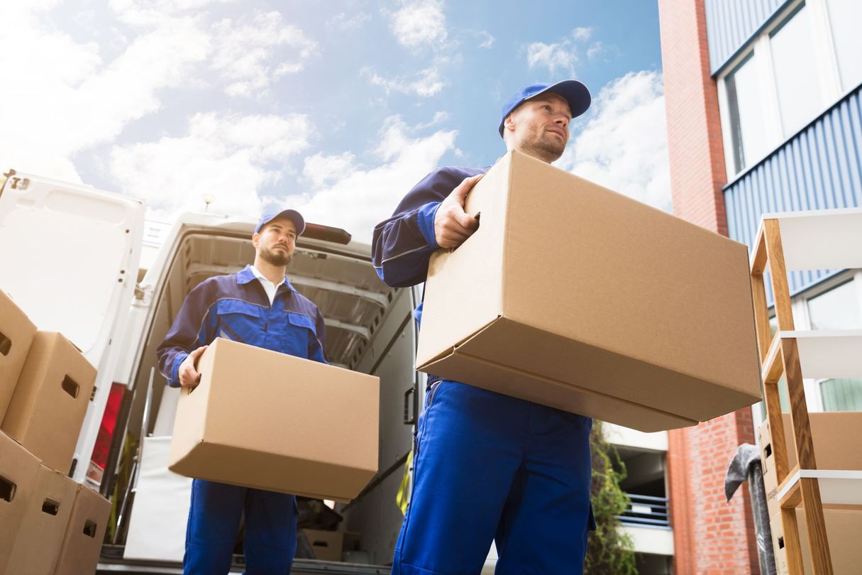 Two movers are carrying boxes out of a van.