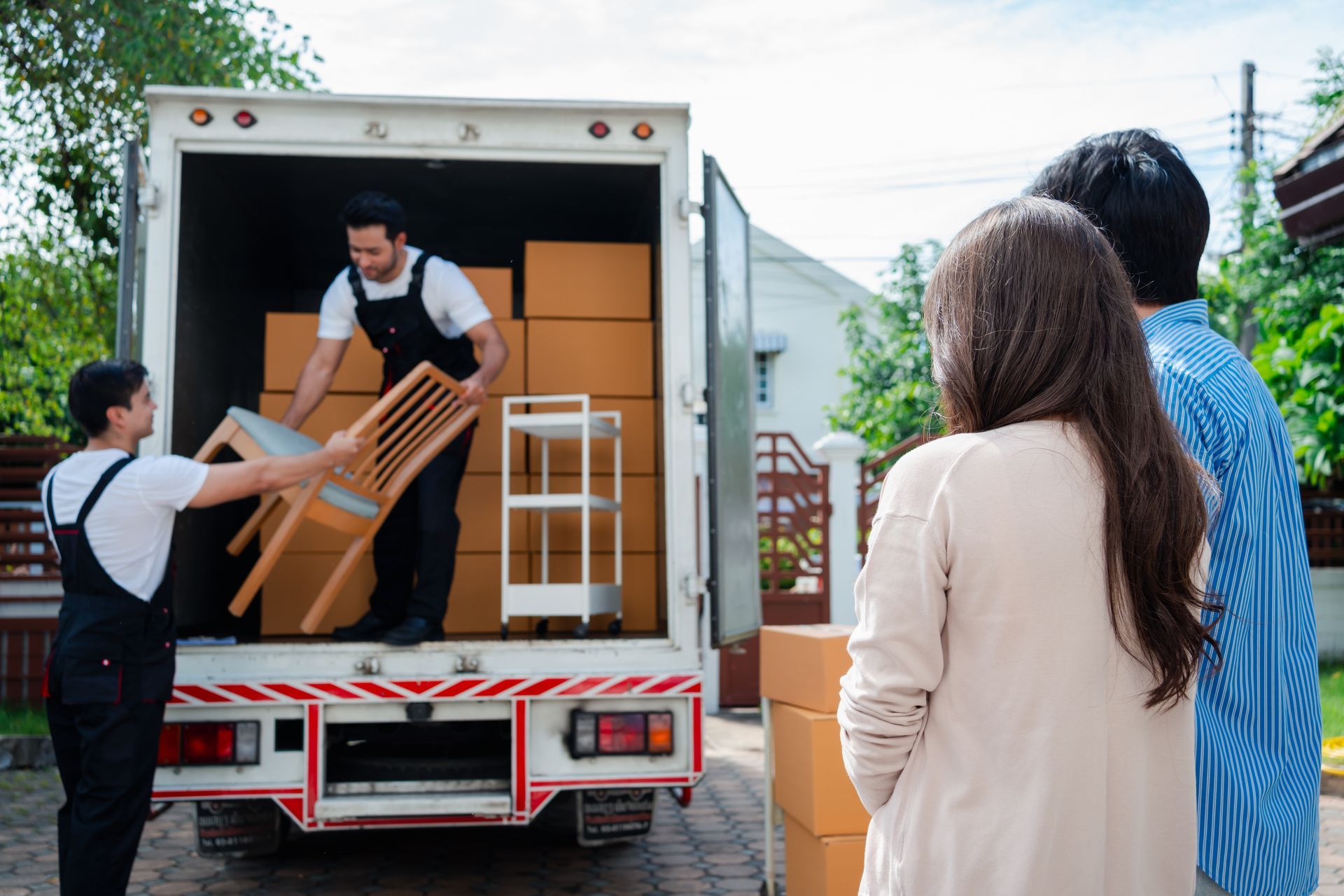 A man is loading a chair into the back of a moving truck.