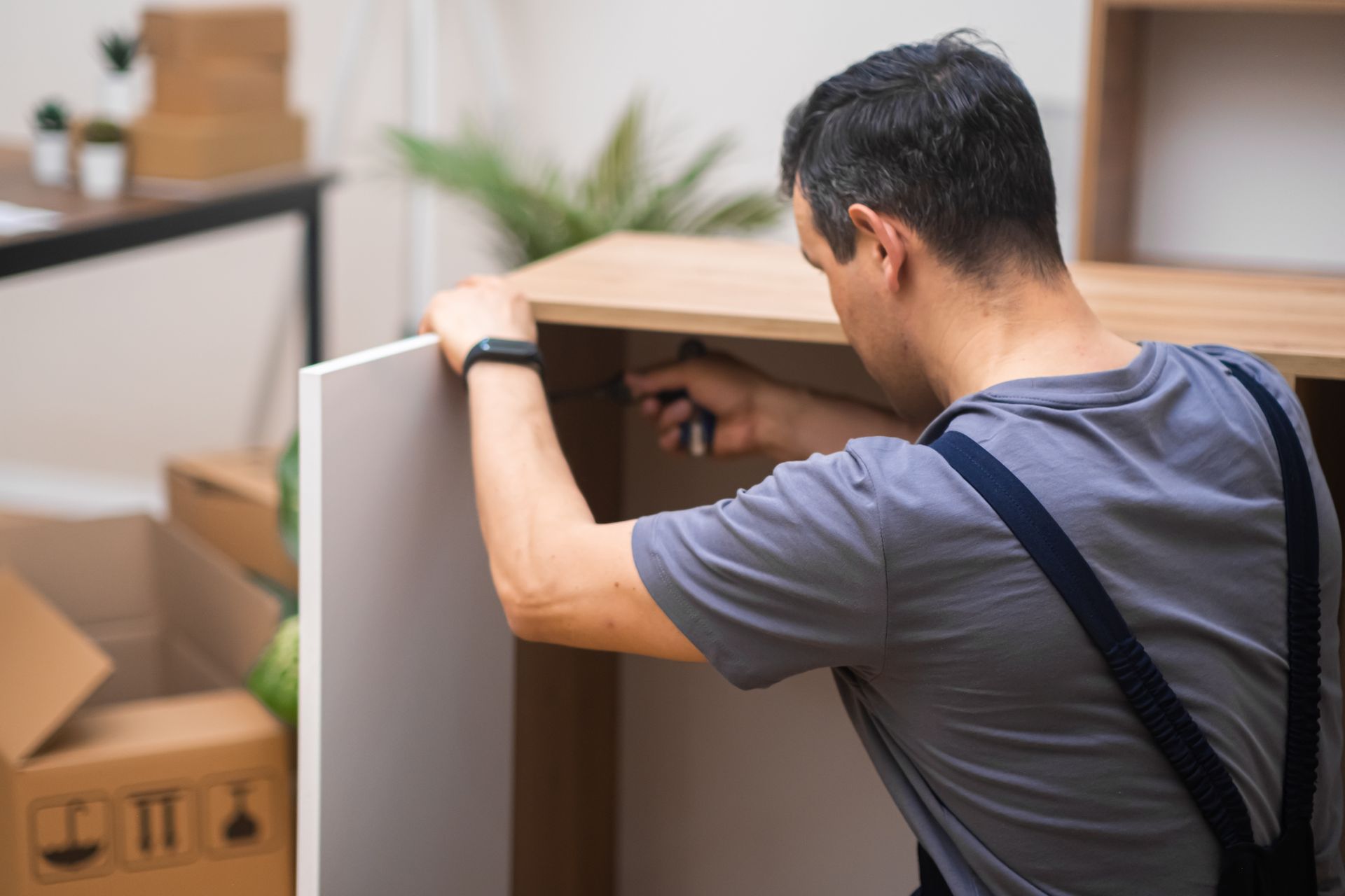 A man is using a screwdriver to fix a piece of furniture.