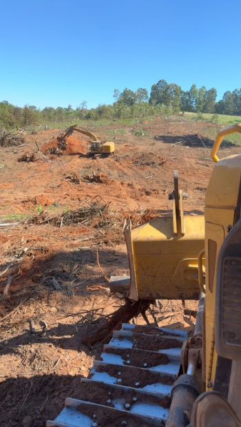 A bulldozer is sitting in the middle of a dirt field.