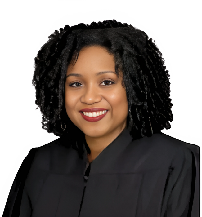 Judge wearing a black robe, smiling with dark curly hair and a dark lipstick.