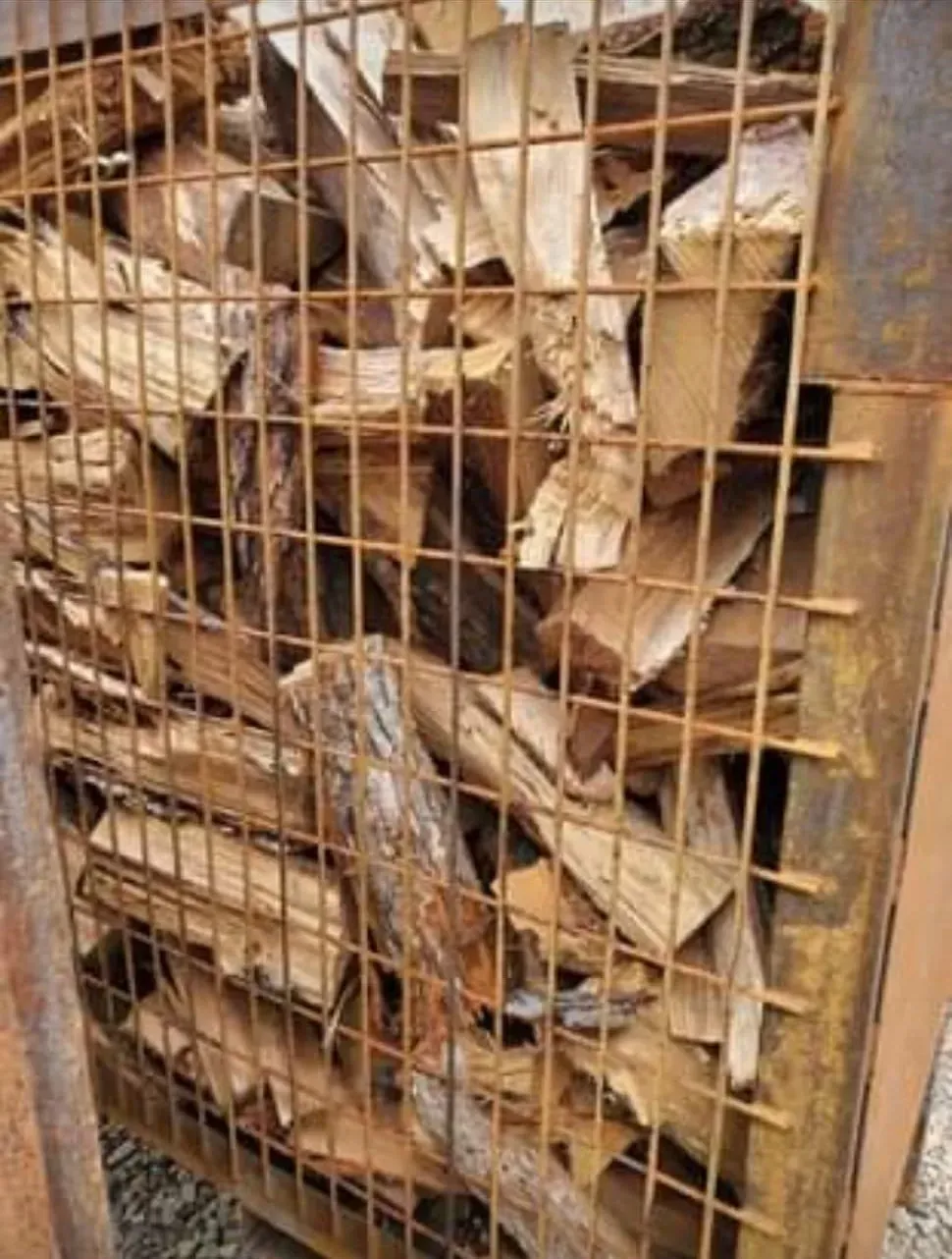 A Pile of Wood Is Behind a Metal Fence - New London, WI - Mid State Firewood