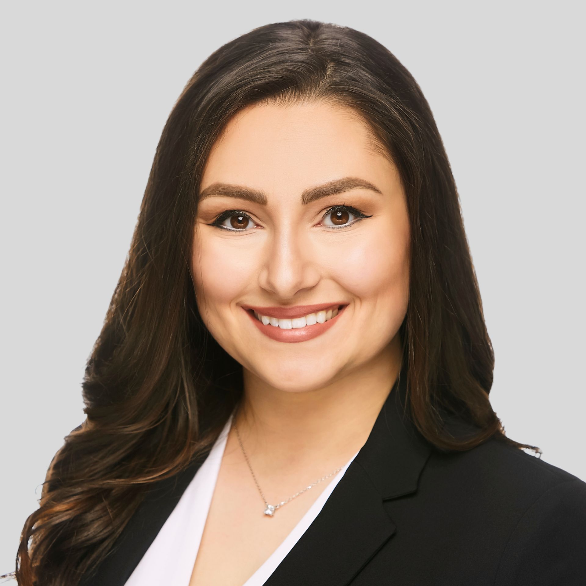 Tima is pictured as a woman in a suit and necklace is smiling in a circle.