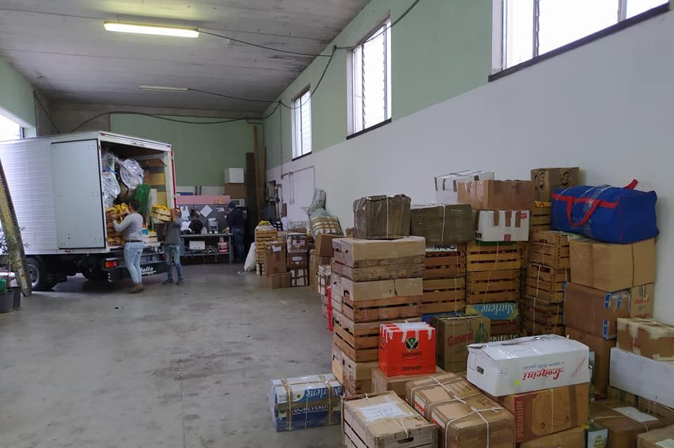 Magazzino con un camion in fase di carico, scatole accatastate, persone al lavoro.