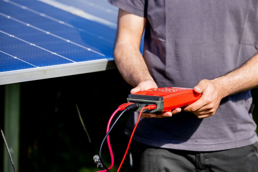 Persona che testa un pannello solare con un dispositivo rosso.